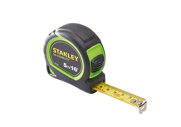 A black and green Stanley hi-visibility tape measure with its yellow measuring tape partially extended, showing both metric and imperial units.