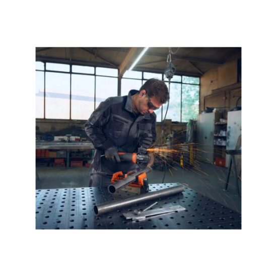 A man wearing safety glasses and ear protection uses an angle grinder to cut a metal pipe on a workbench, with sparks flying in a workshop.