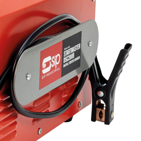 Close-up of a SIP Industrial Startmaster DSC200B digital starter charger with a black cable and clamp attached, and a silver plate displaying the product label on an orange metal surface.