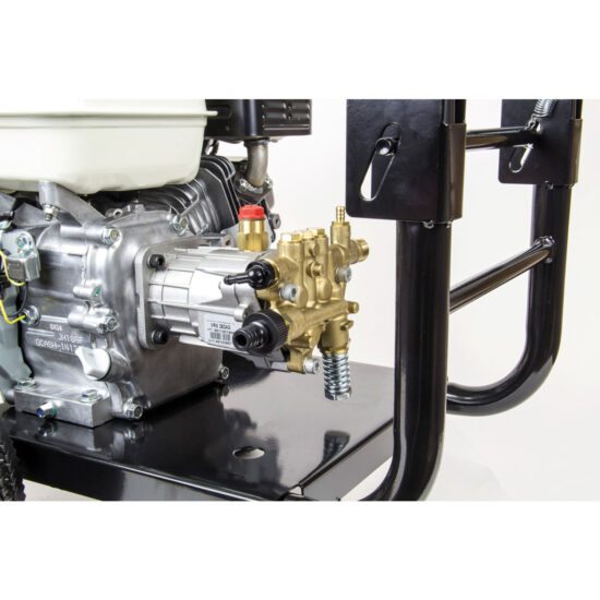 Close-up of a pressure washer pump mounted on a black metal frame, showing detailed components including a brass valve, silver engine parts, and hoses.