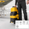 A person in black workwear stands indoors, holding the handle of a yellow and black Mirka vacuum extractor on wheels. Inset icons highlight features such as multiple sockets, a powerful motor, compact handling, and ergonomics.