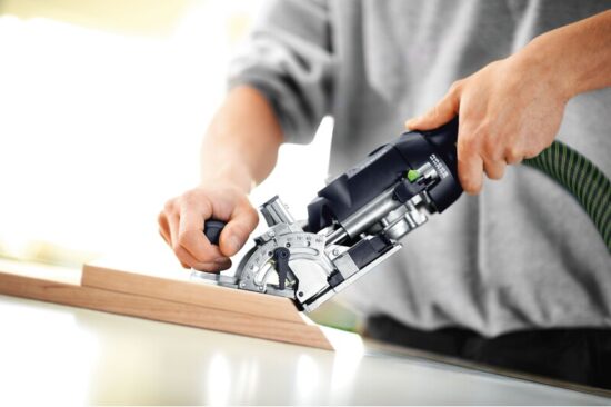 A person using a power tool to cut a piece of wood.