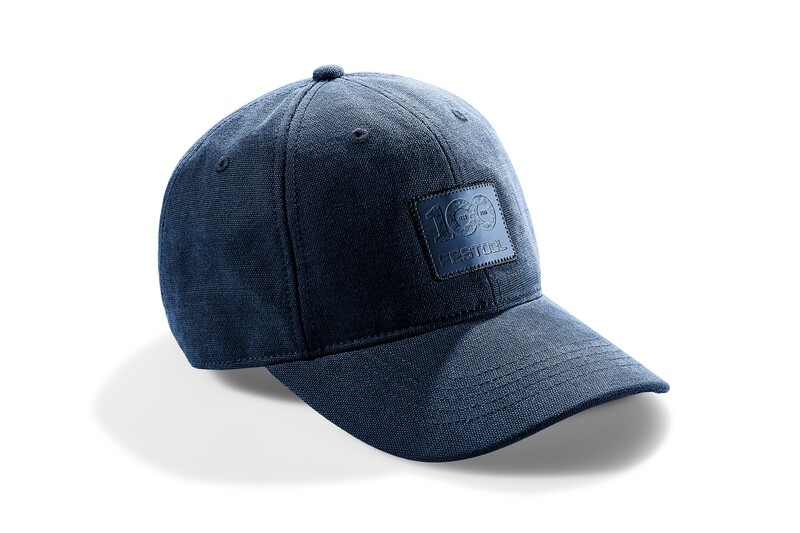 A blue denim baseball cap with a curved brim and a patch on the front that reads 100 Festival. The cap is positioned at an angle on a white background, casting a shadow.