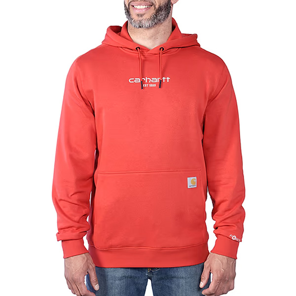 A man stands smiling with hands by his sides, in blue jeans and a red sweatshirt with a front pocket and white logo.