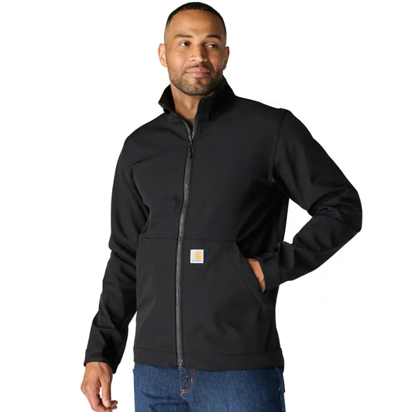 A man in a black zip-up jacket, blue jeans, and a Bordeaux T-shirt stands with one hand in his pocket, smiling to the side.