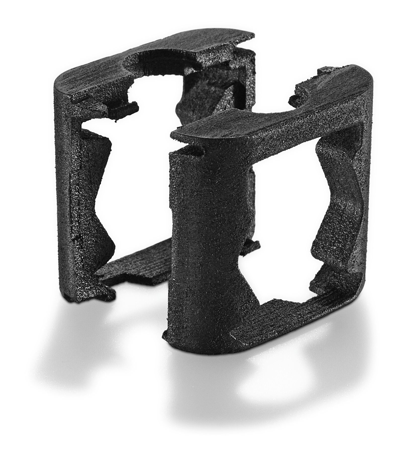 Two black, rectangular plastic clips with cut-out centers and jagged edges, standing upright on a white background with shadows.