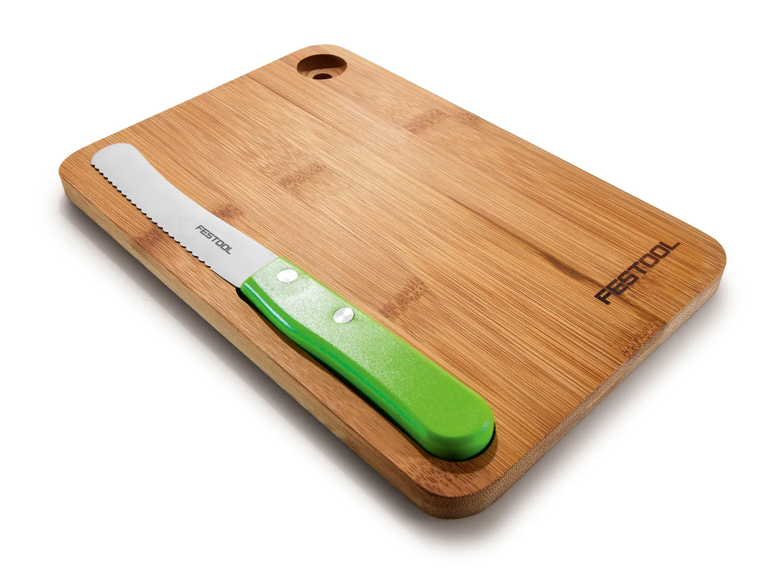 A wooden cutting board with a hole in one corner and a green-handled serrated knife resting on top.