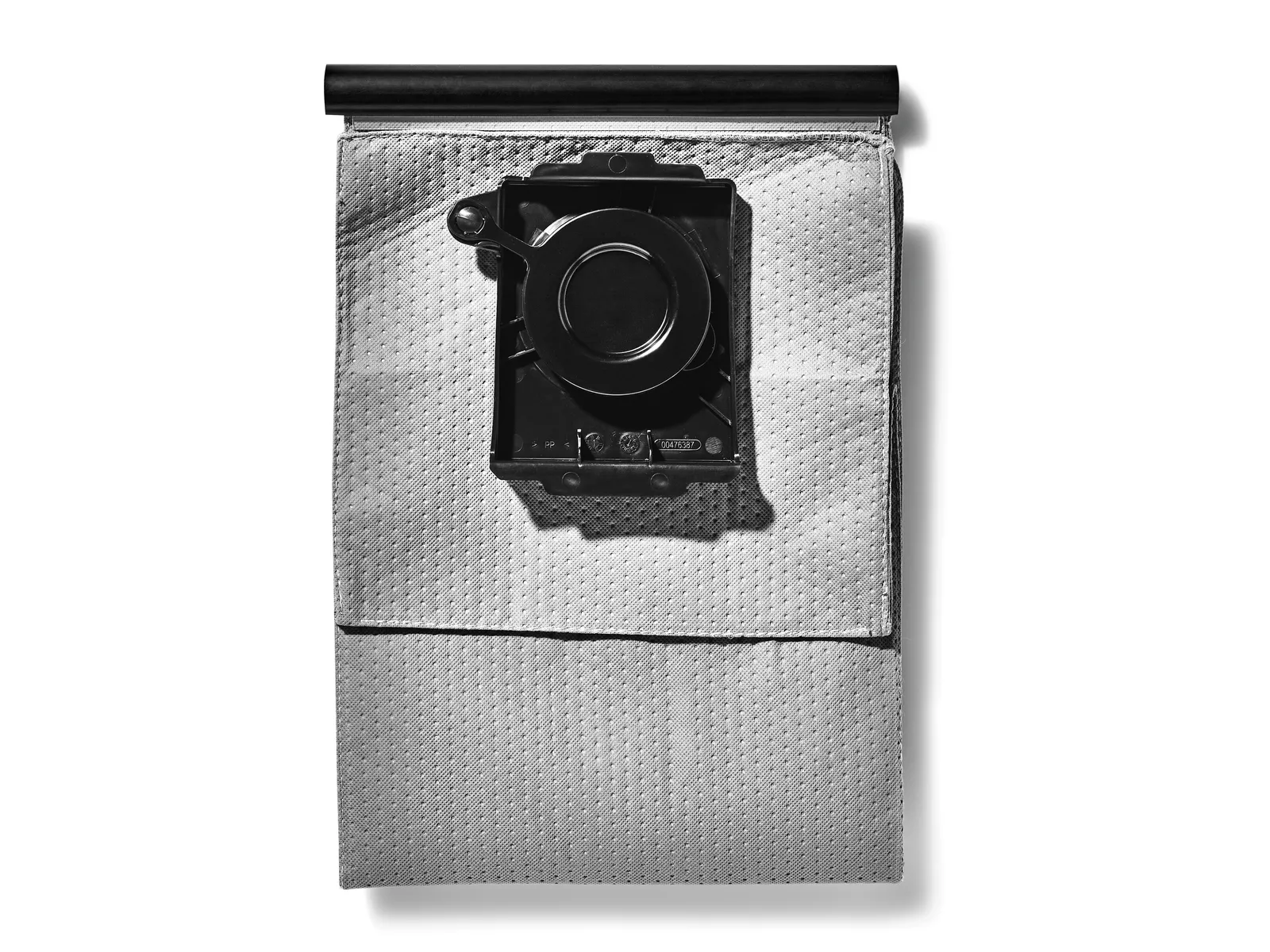 A white rectangular Festool filter bag with a black plastic attachment lies on a flat surface, casting a shadow to the right.