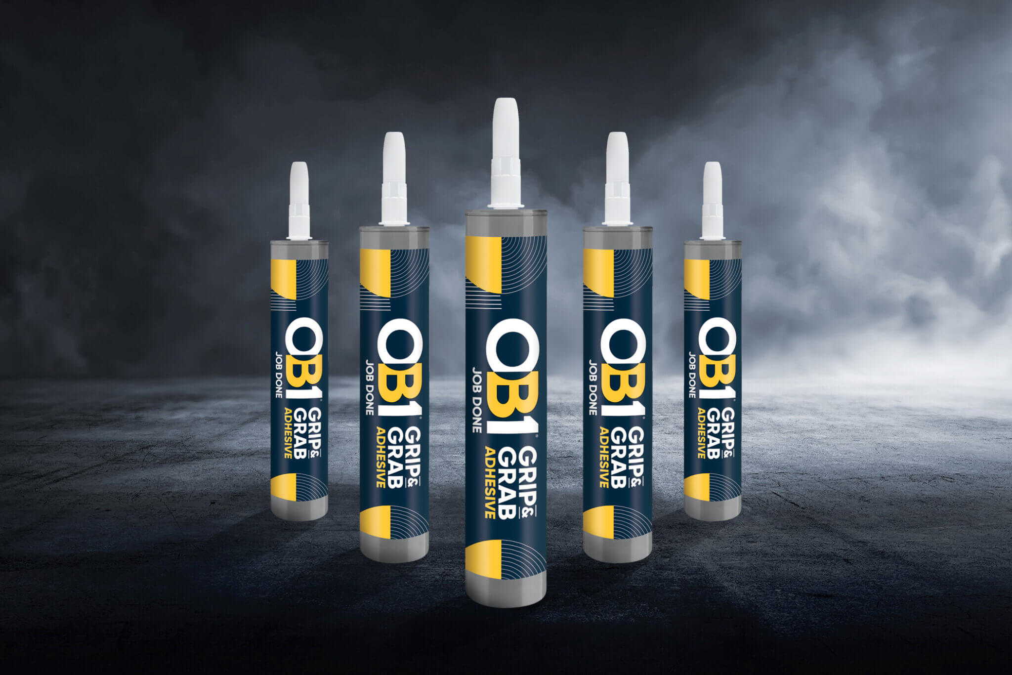 Five OB1 Grip & Grab Adhesive 290ml tubes stand upright on a dark textured surface with a smoky background, white nozzles, blue and yellow labels.