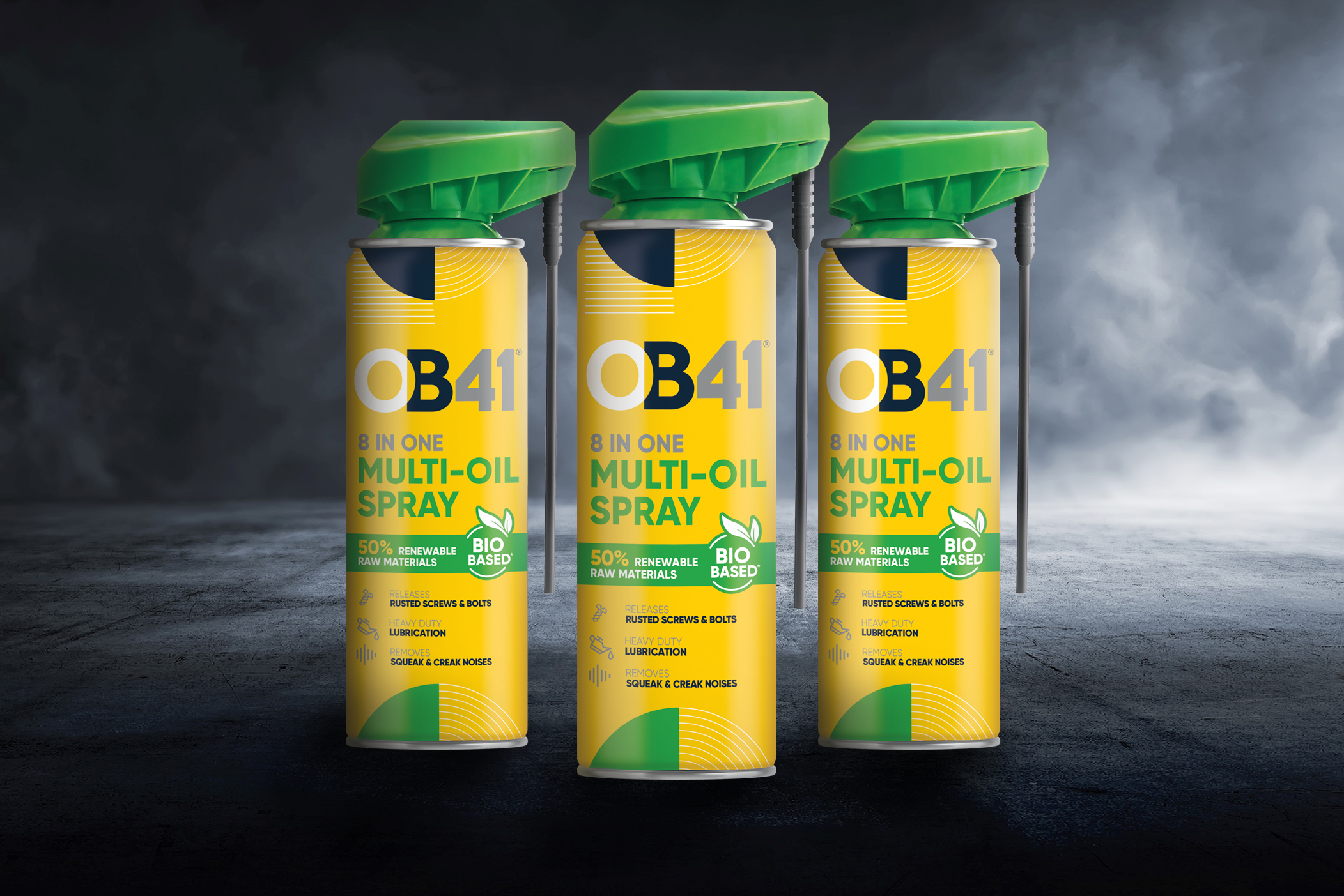Three OB41 8 in 1 multi oil spray cans with yellow and green trigger sprayers on a dark surface, smoky blurred background. Uses bio-based formulas.