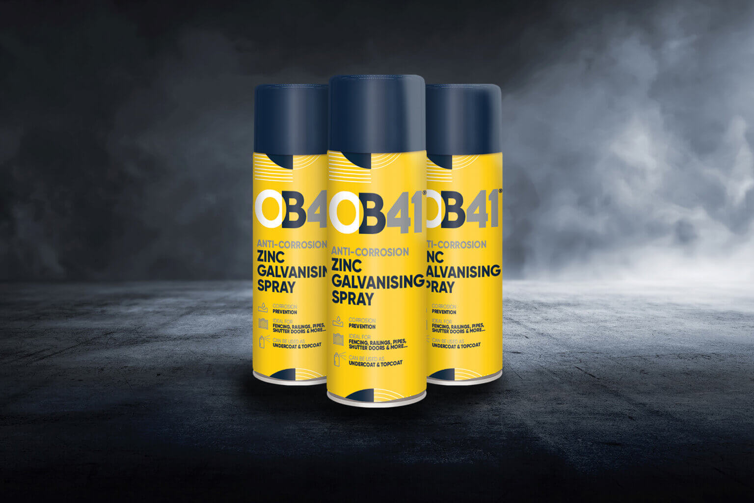 Three 500ml cans of OB1 Paint & Varnish Remover stand upright on a dark textured surface with a dramatic smoky background.