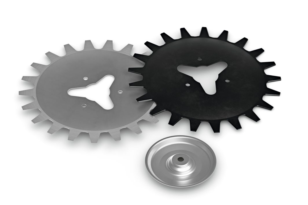 Two Stihl RG/RG-KM replacement blades, one silver and one black, with triangular centres, lie side by side above a small silver disc.