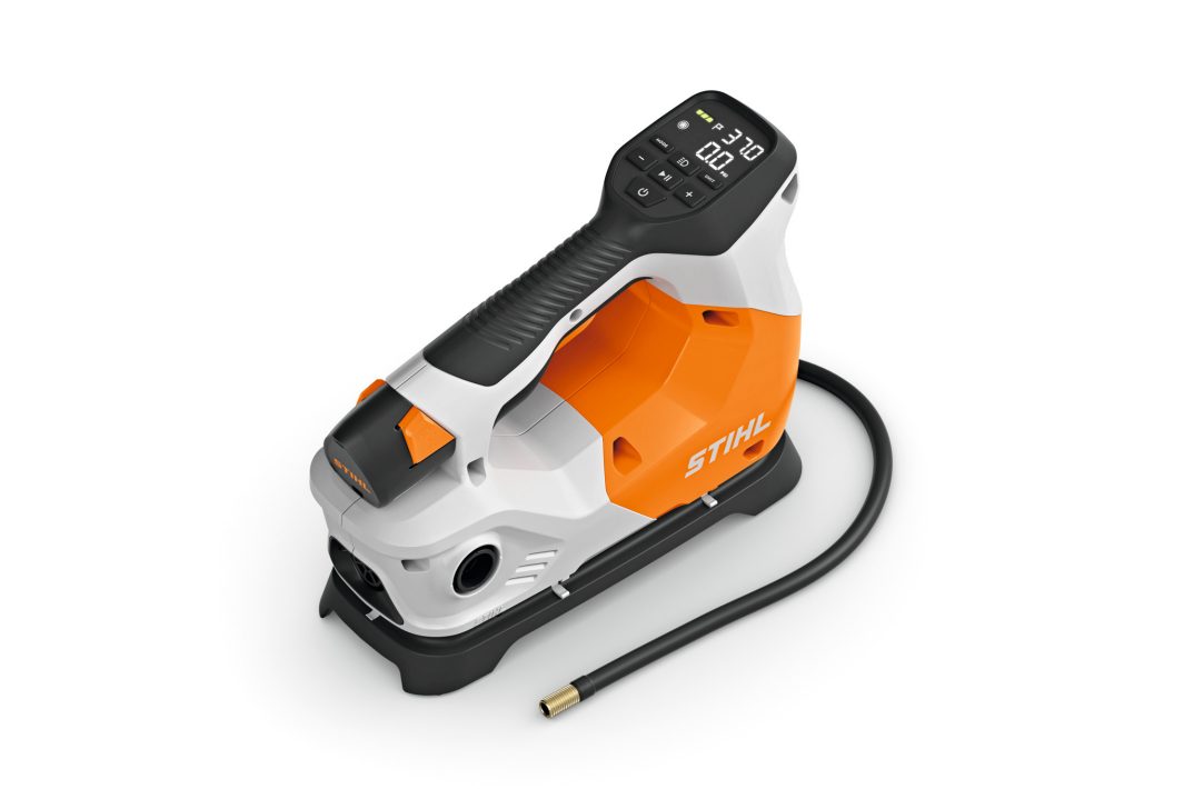 A compact handheld STIHL pressure washer in orange, white, and black with a digital control panel, attached hose, and sturdy handle.