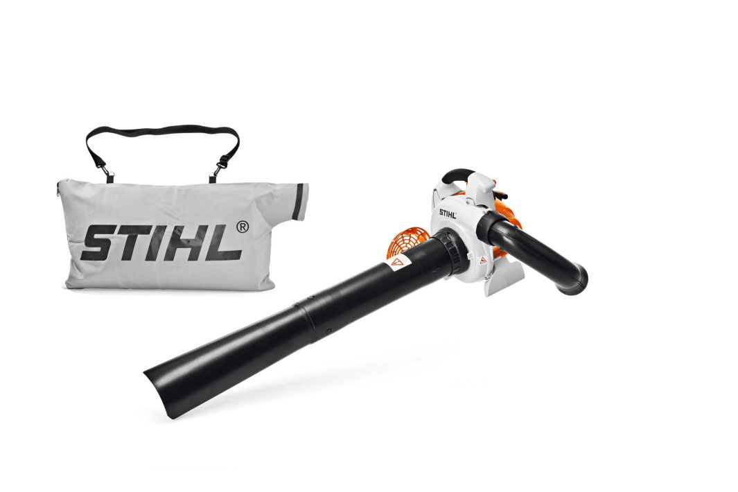 The Stihl SH 56 Shredder/Vacuum with a long black nozzle and orange-and-white body sits next to a grey carrying bag on white.